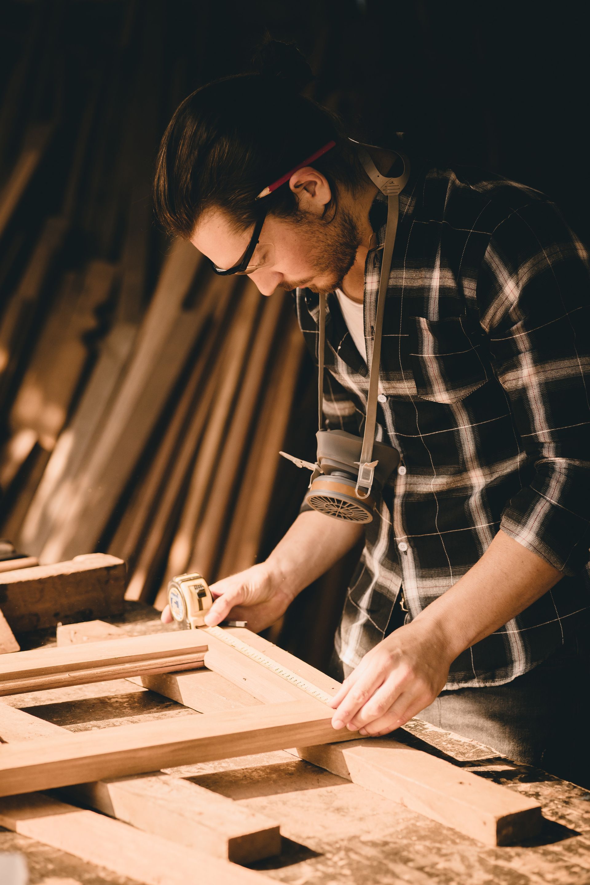 A man is measuring a piece of wood with a tape measure.