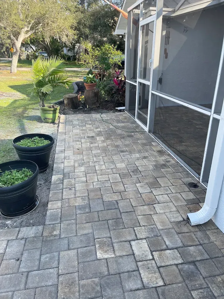 Patio with gray pavers, potted plants, and screened enclosure.