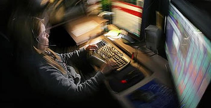 A woman is sitting at a desk typing on a computer keyboard.