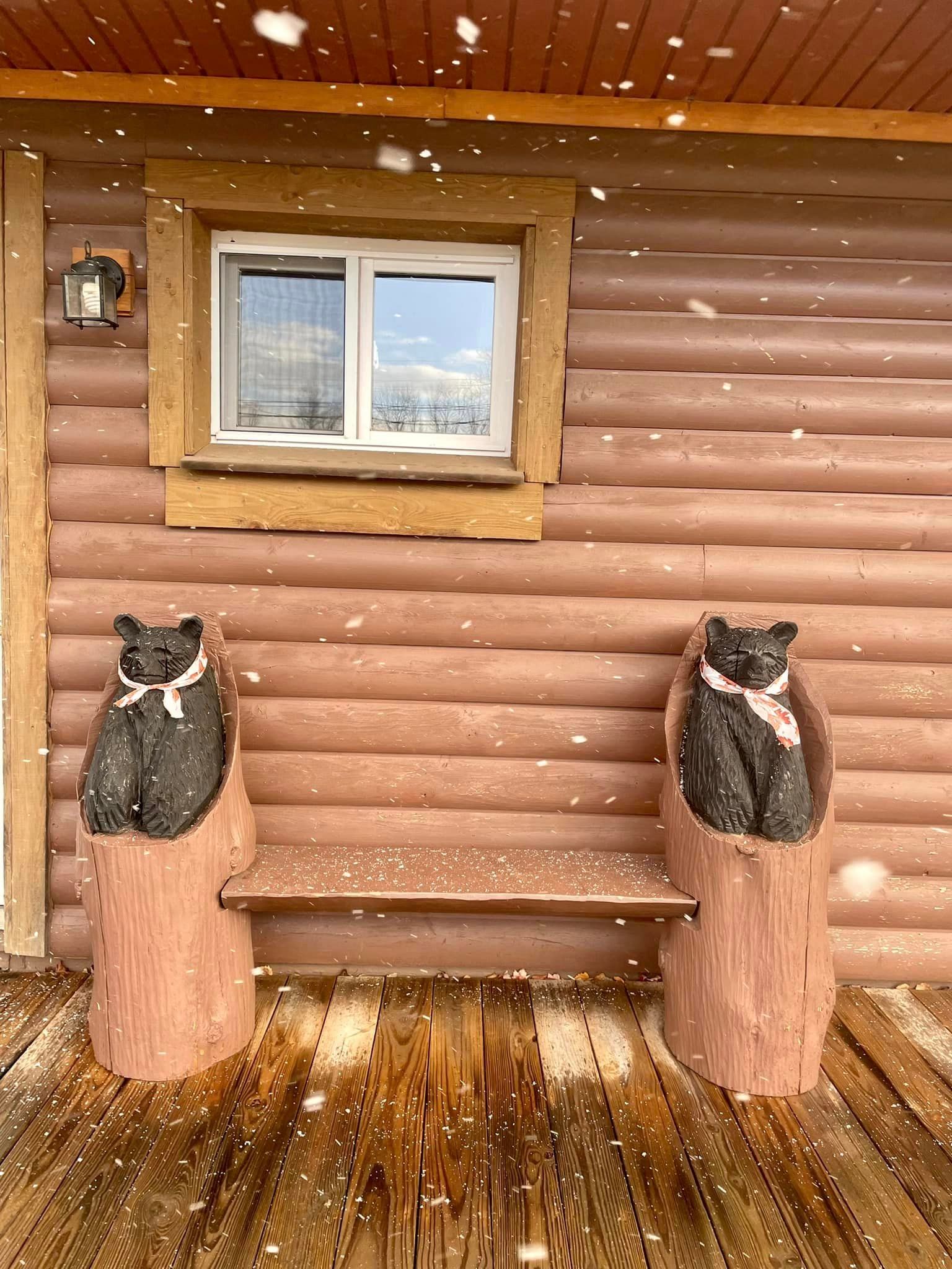 two carved bears are sitting on a bench in front of a log cabin .
