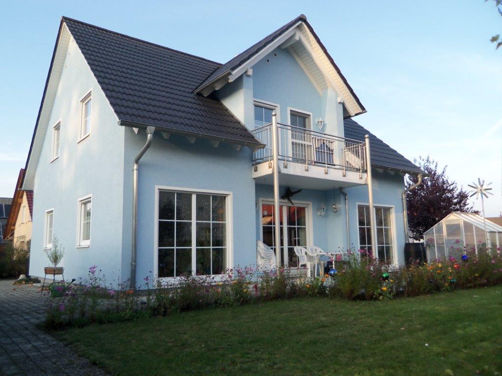Ein blaues Haus mit einem schwarzen Dach und einem Balkon