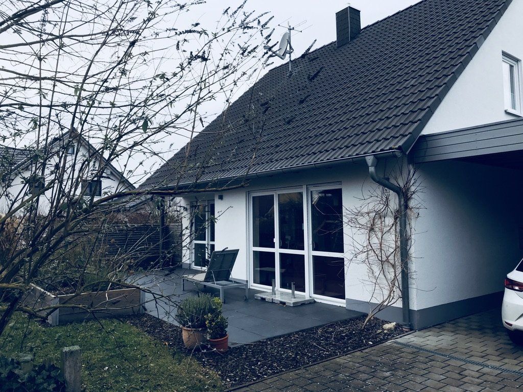 Ein weißes Haus mit einem davor geparkten Auto.