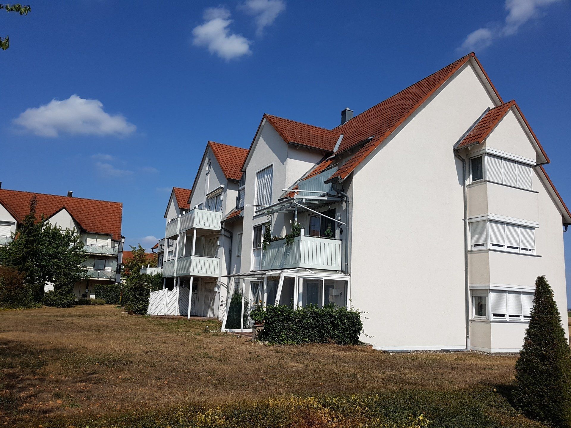 Ein weißes Gebäude mit rotem Dach und Balkonen