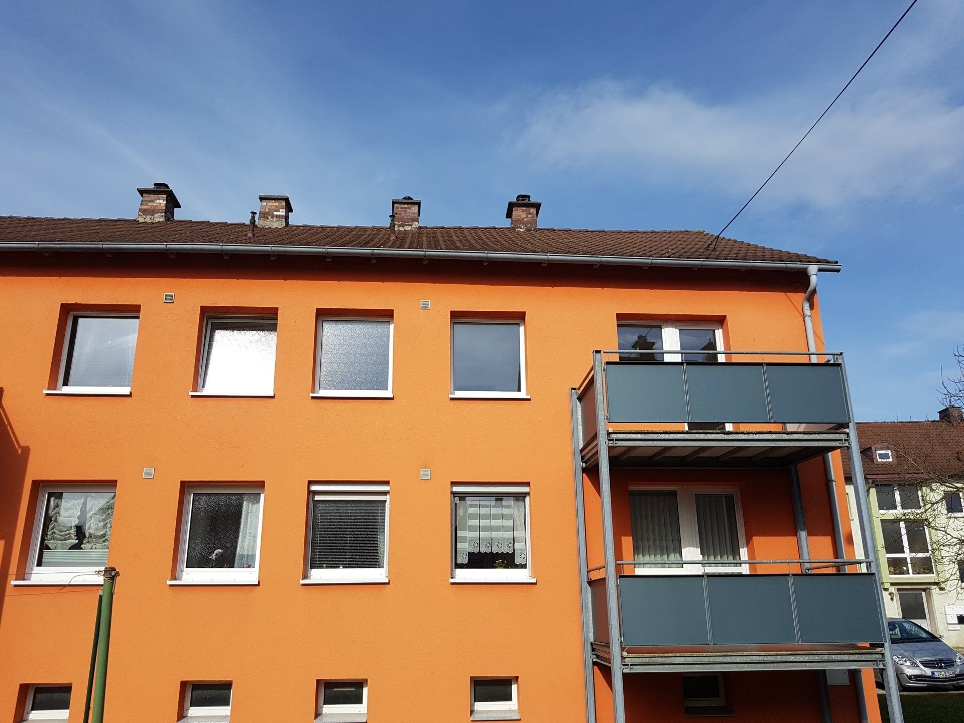 Ein orangefarbenes Gebäude mit Balkonen und einem blauen Himmel im Hintergrund