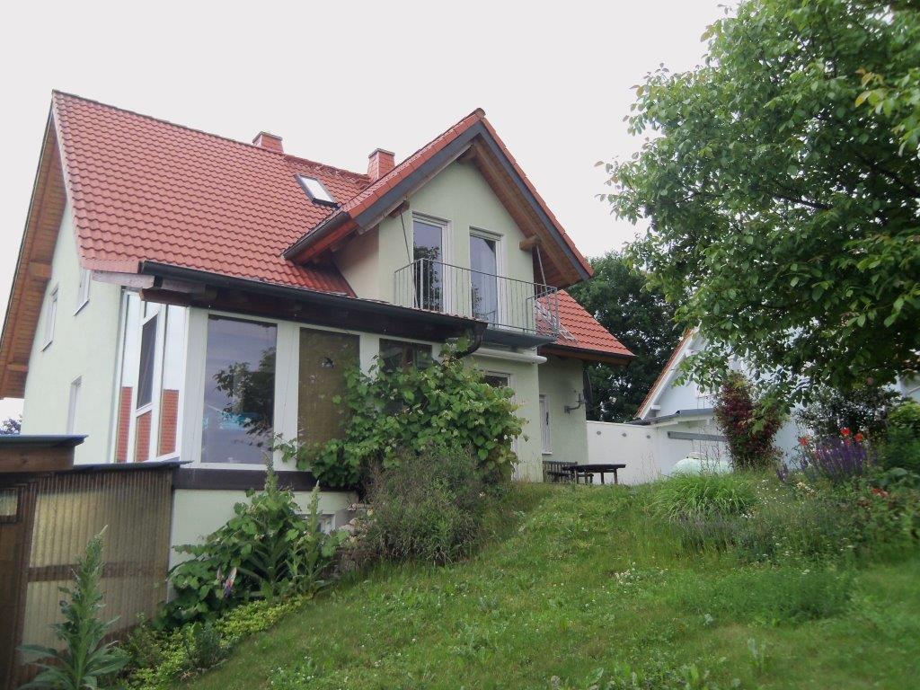 Ein weißes Haus mit einem roten Dach und einem Balkon