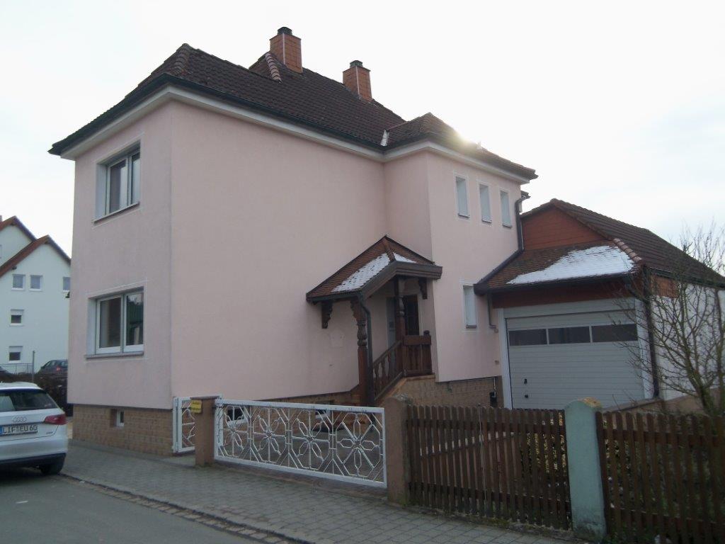 Ein rosa Haus mit einem davor geparkten Auto