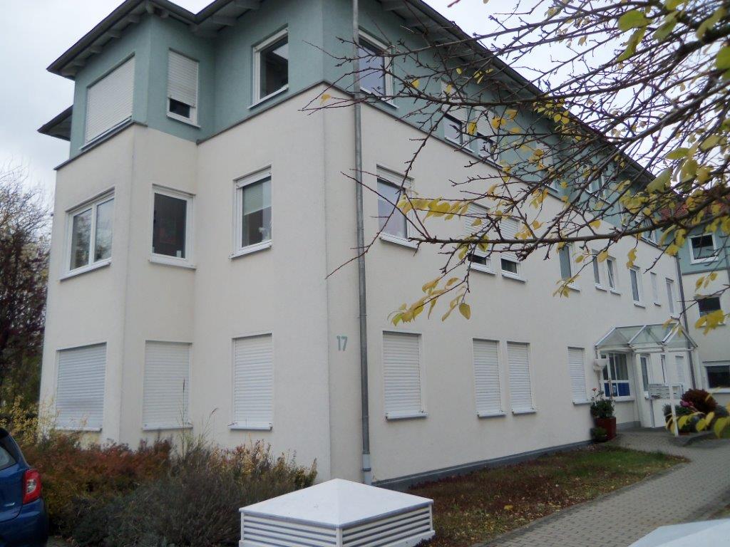 Ein großes weiß-blaues Gebäude mit einem davor geparkten blauen Auto