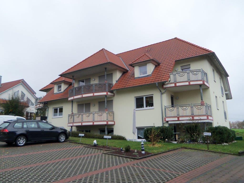 Ein Auto ist vor einem großen Haus mit Balkonen geparkt