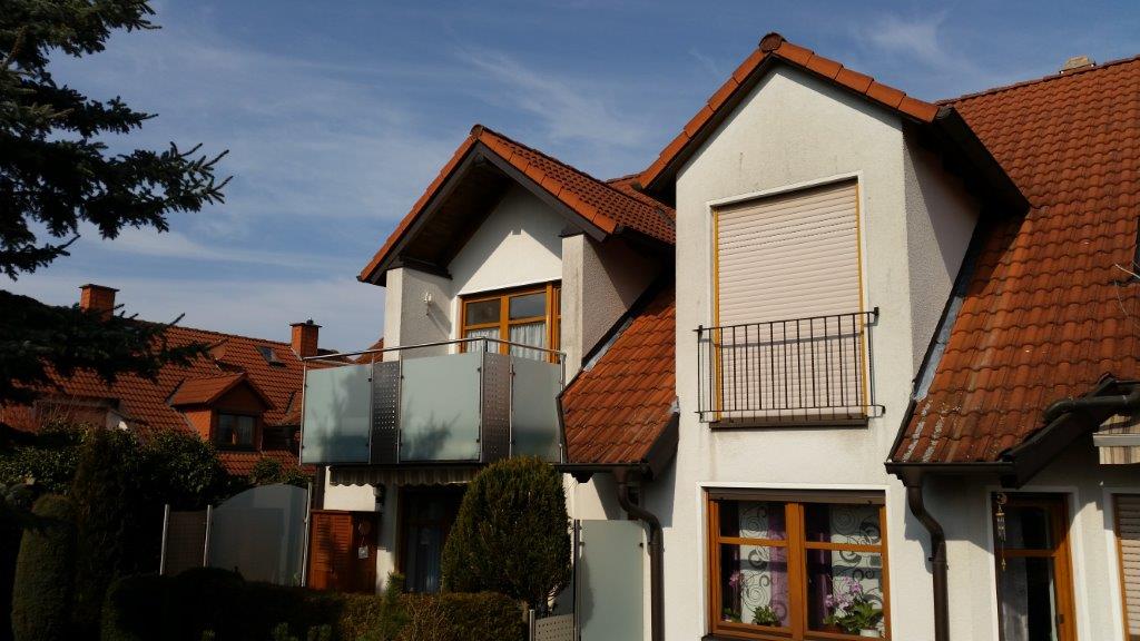 Ein weißes Haus mit einem roten Ziegeldach und einem Balkon