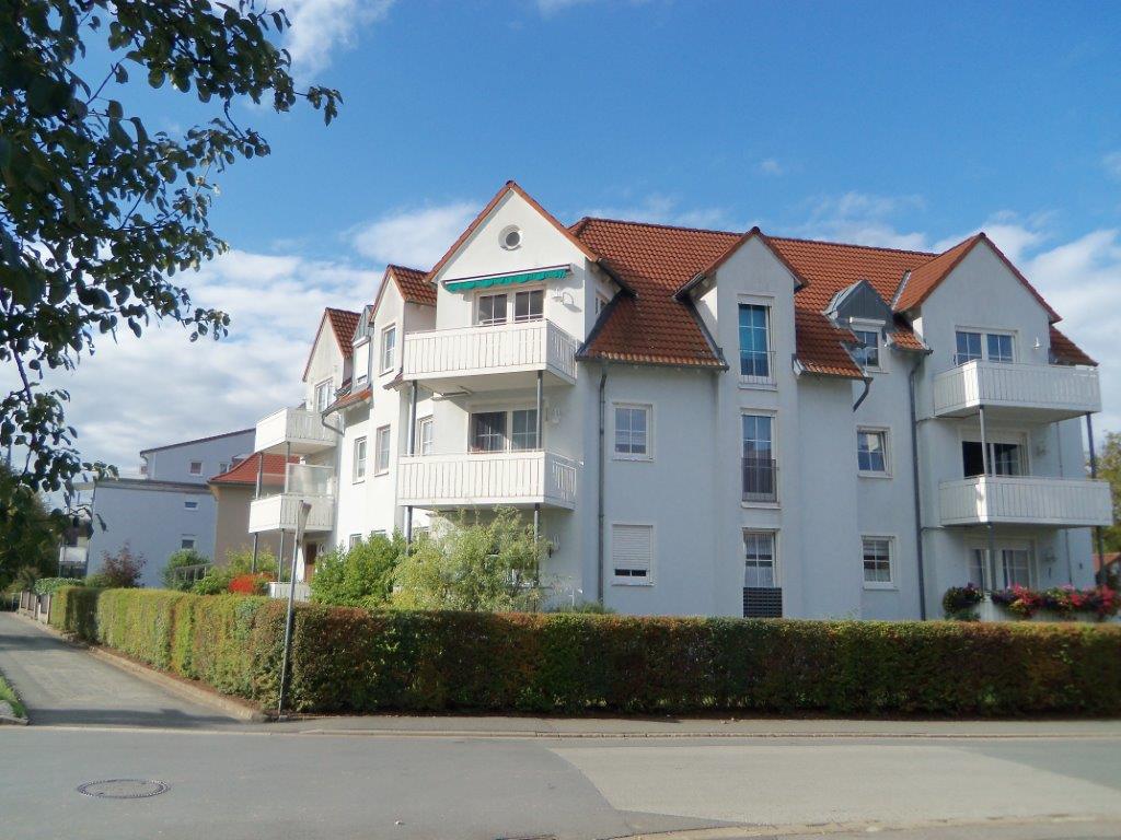 Ein großes weißes Gebäude mit einem roten Dach und Balkonen