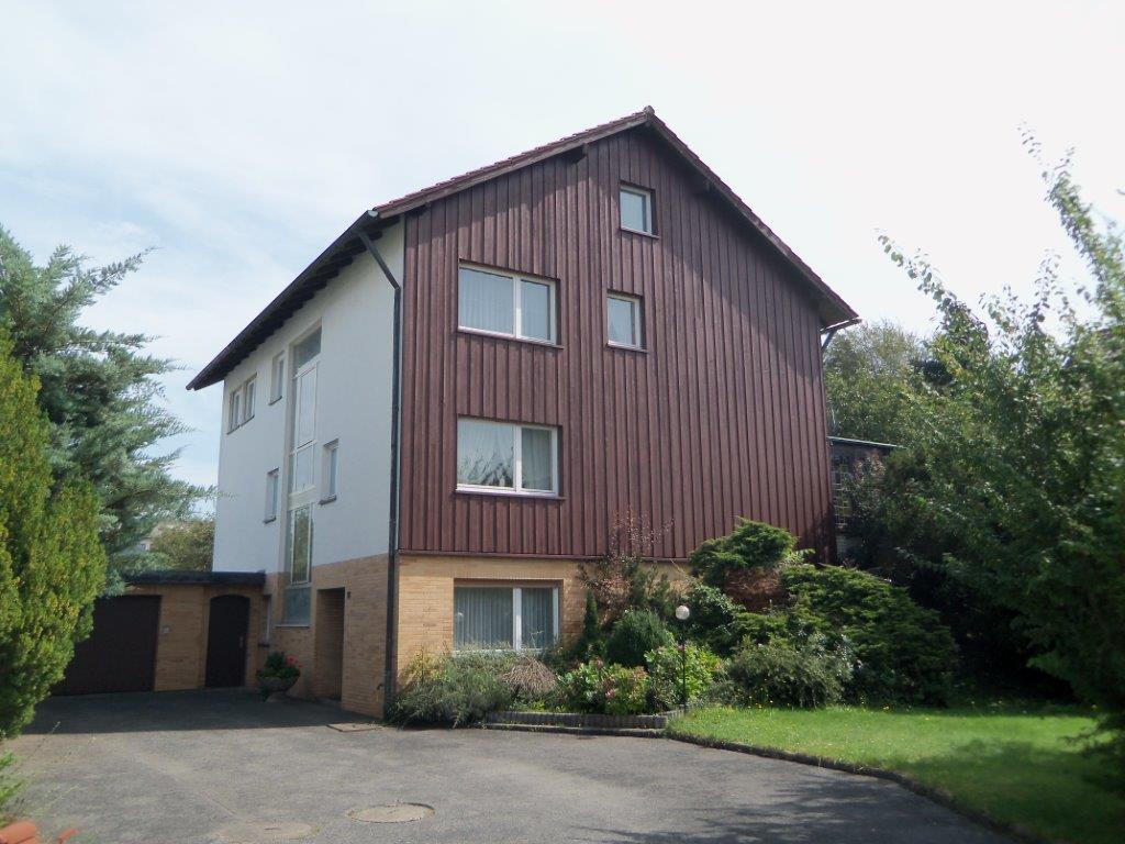 Ein braun-weißes Haus mit einer Auffahrt davor