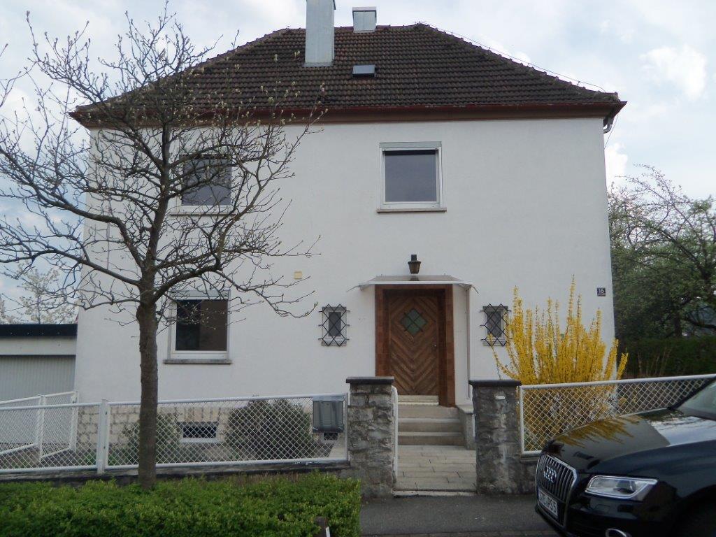 Ein weißes Haus mit einem davor geparkten schwarzen Auto