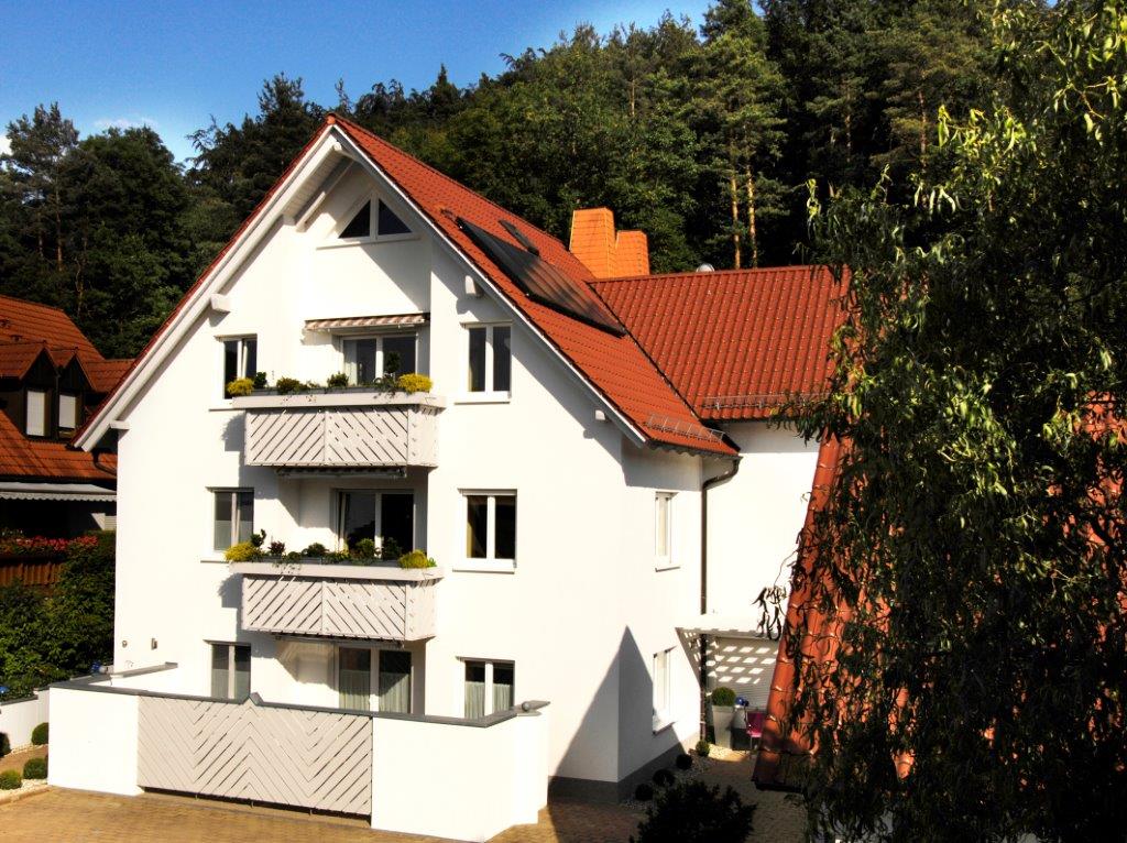 Ein weißes Haus mit einem roten Dach ist von Bäumen umgeben