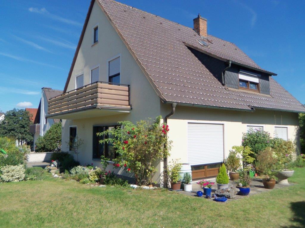 Ein weißes Haus mit einem braunen Dach und einem Balkon