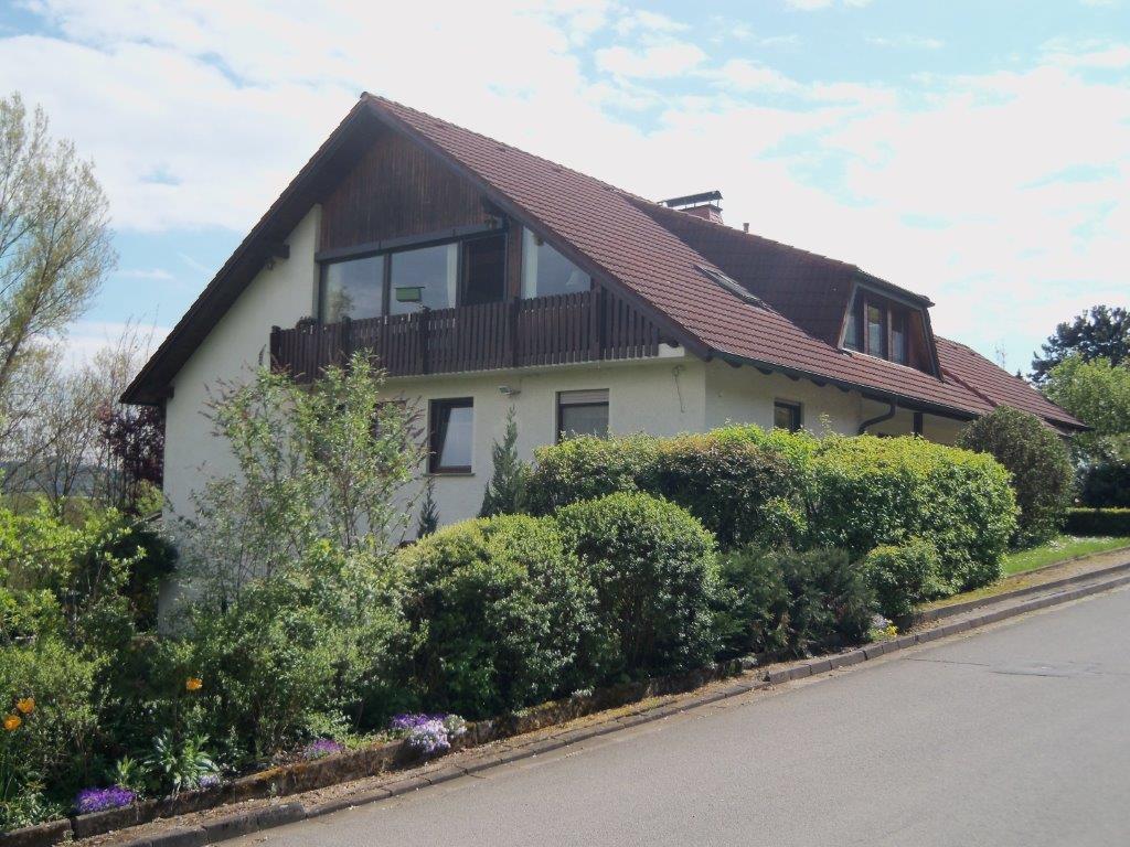 Ein weißes Haus mit einem braunen Dach steht auf einem Hügel