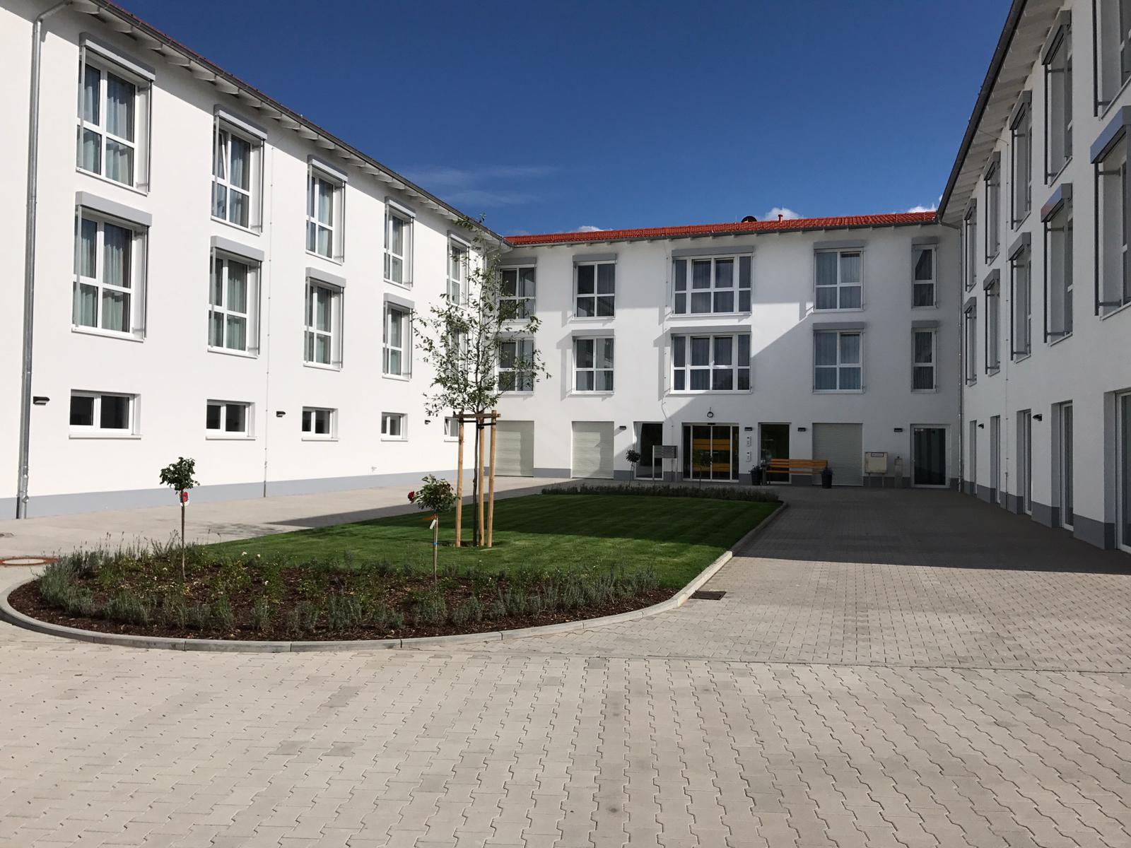 Ein großes weißes Gebäude mit einem runden Innenhof davor.