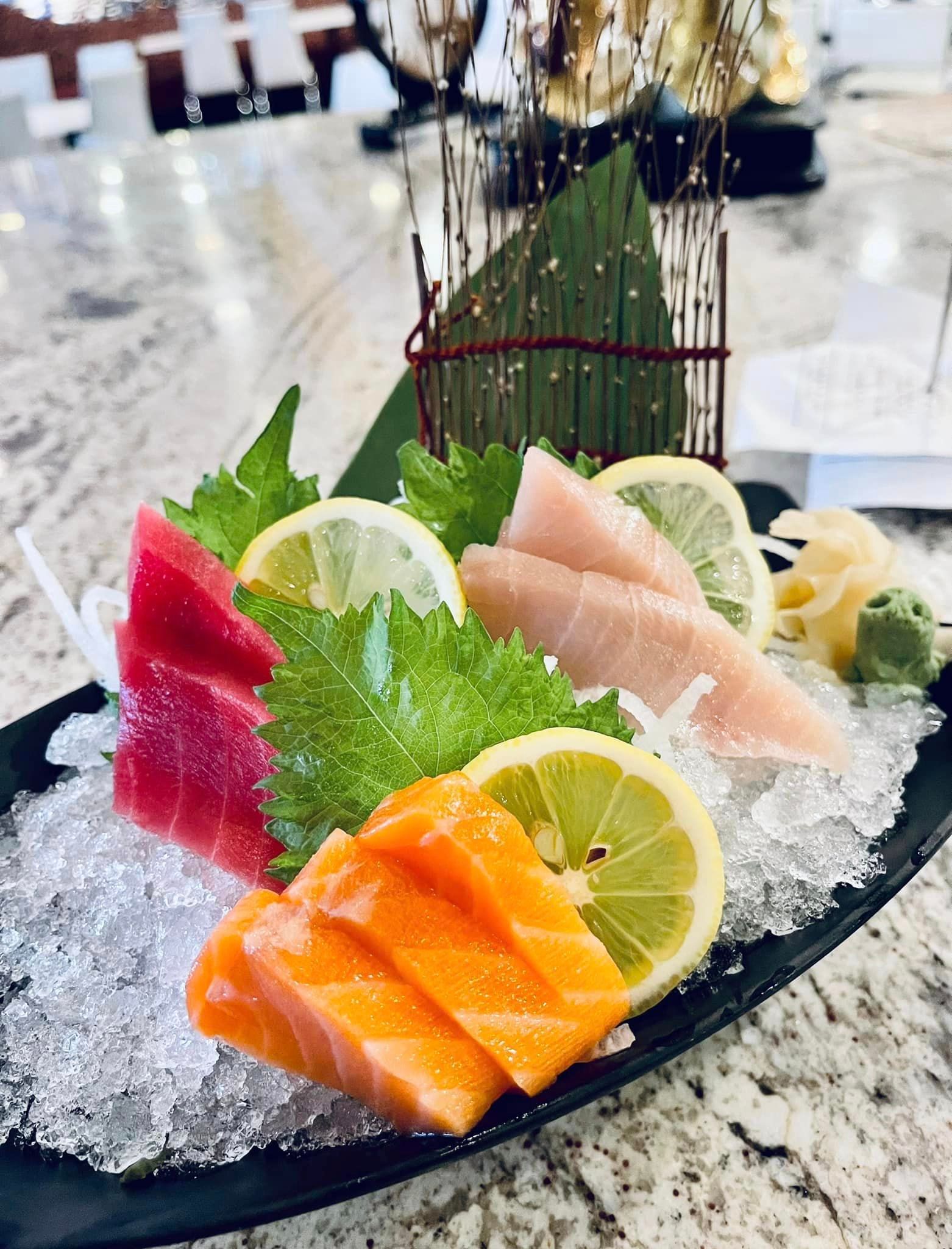 A close up of a plate of sushi on ice on a table.