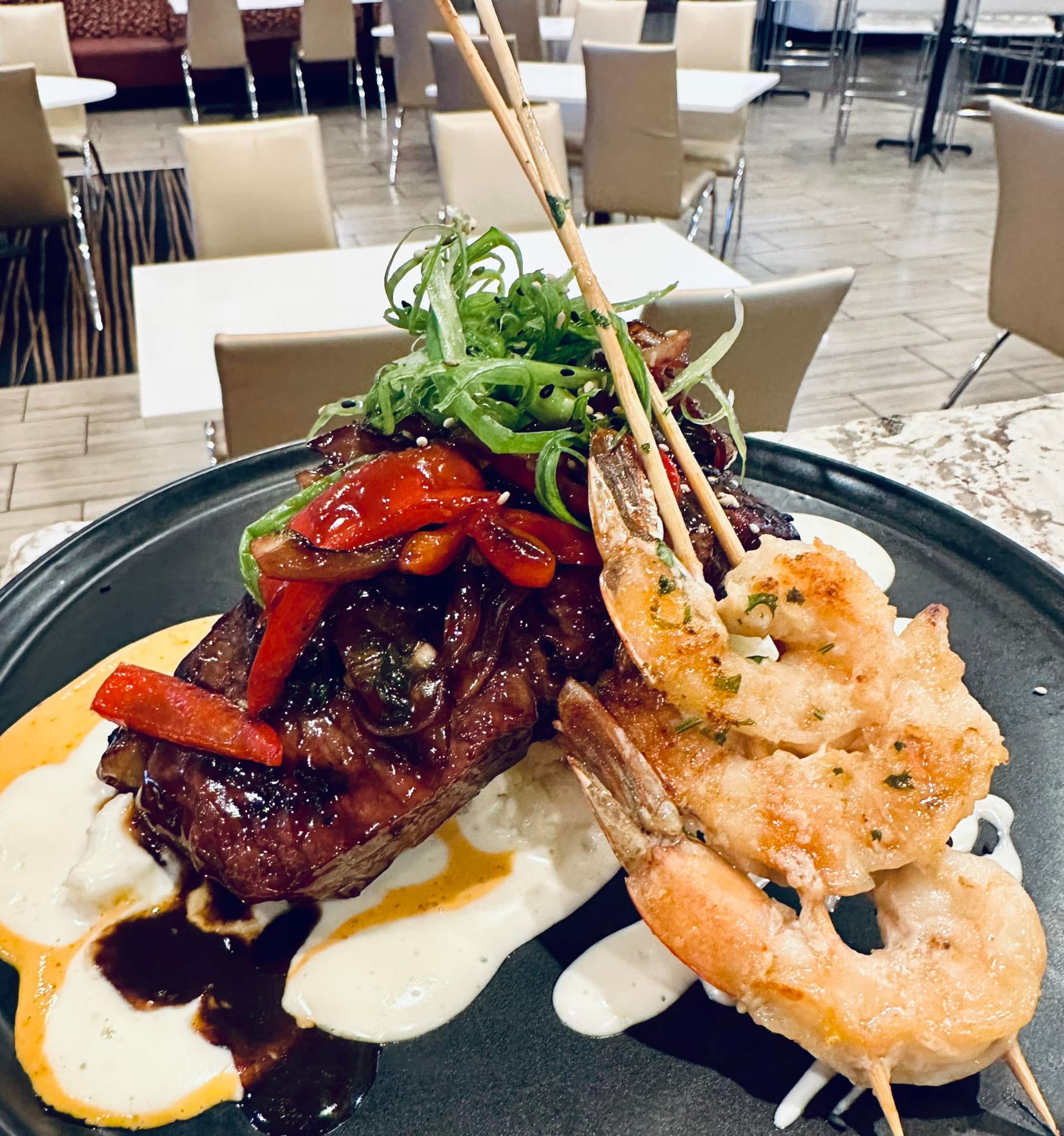 A plate of food with meat and shrimp on a table in a restaurant.