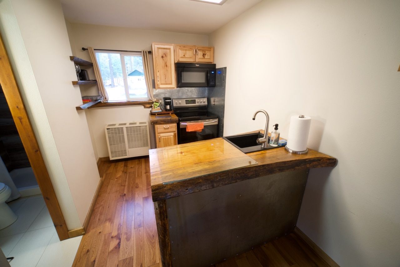 A kitchen with a sink , stove , microwave and refrigerator.