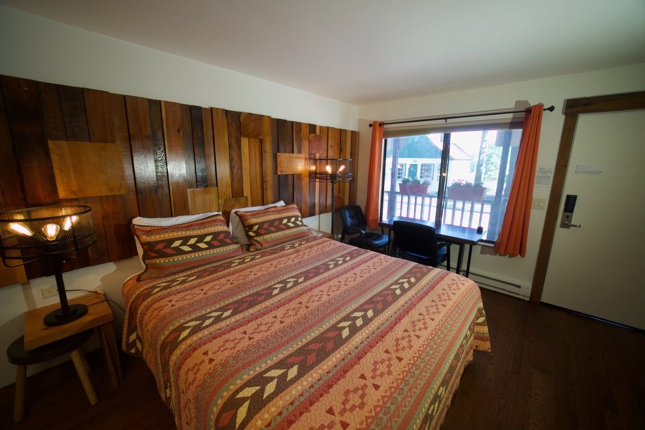 A hotel room with a king size bed and a large window.