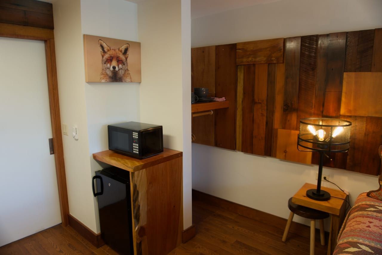 There is a picture of a fox on the wall above the refrigerator in the room.