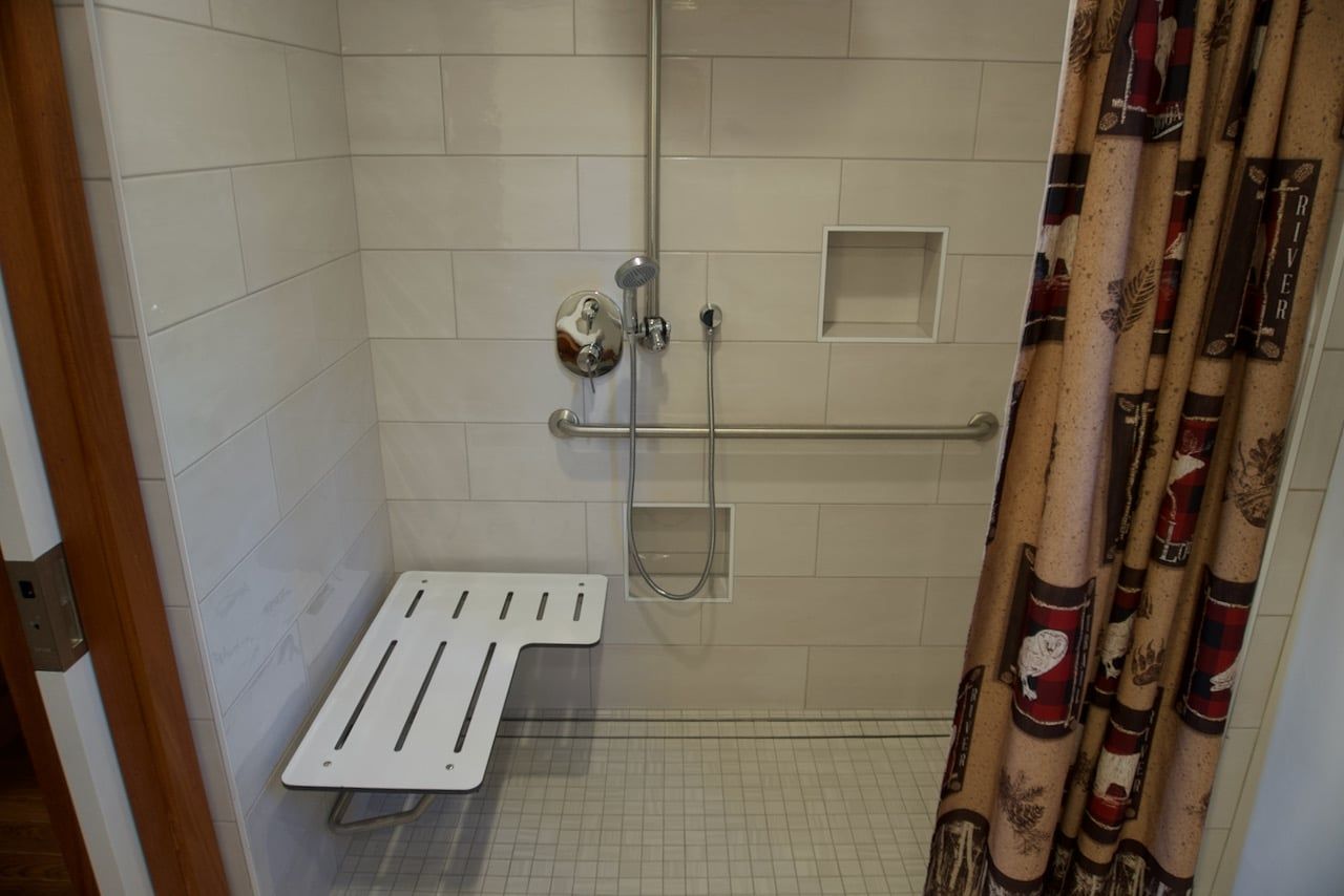 A handicapped shower with a bench and a shower curtain.