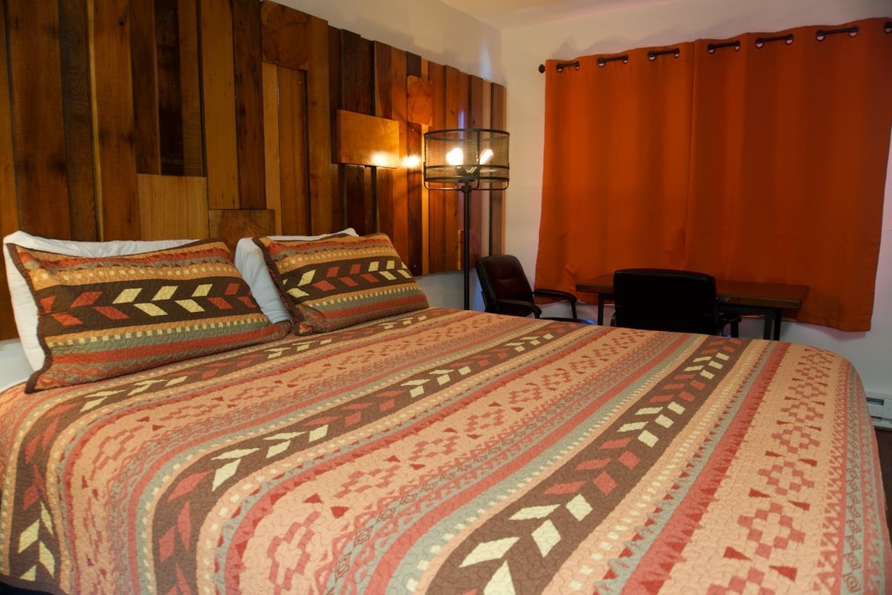 A bed with a colorful blanket and pillows in a hotel room.