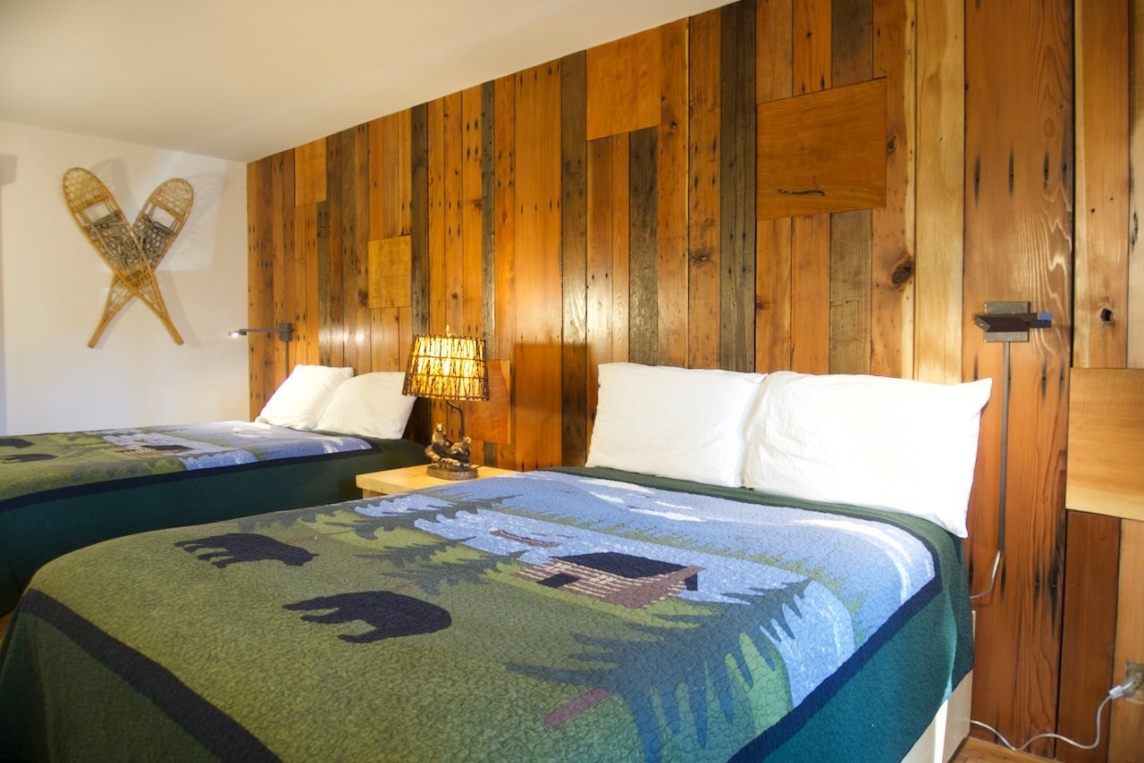 A hotel room with two beds and a wooden wall