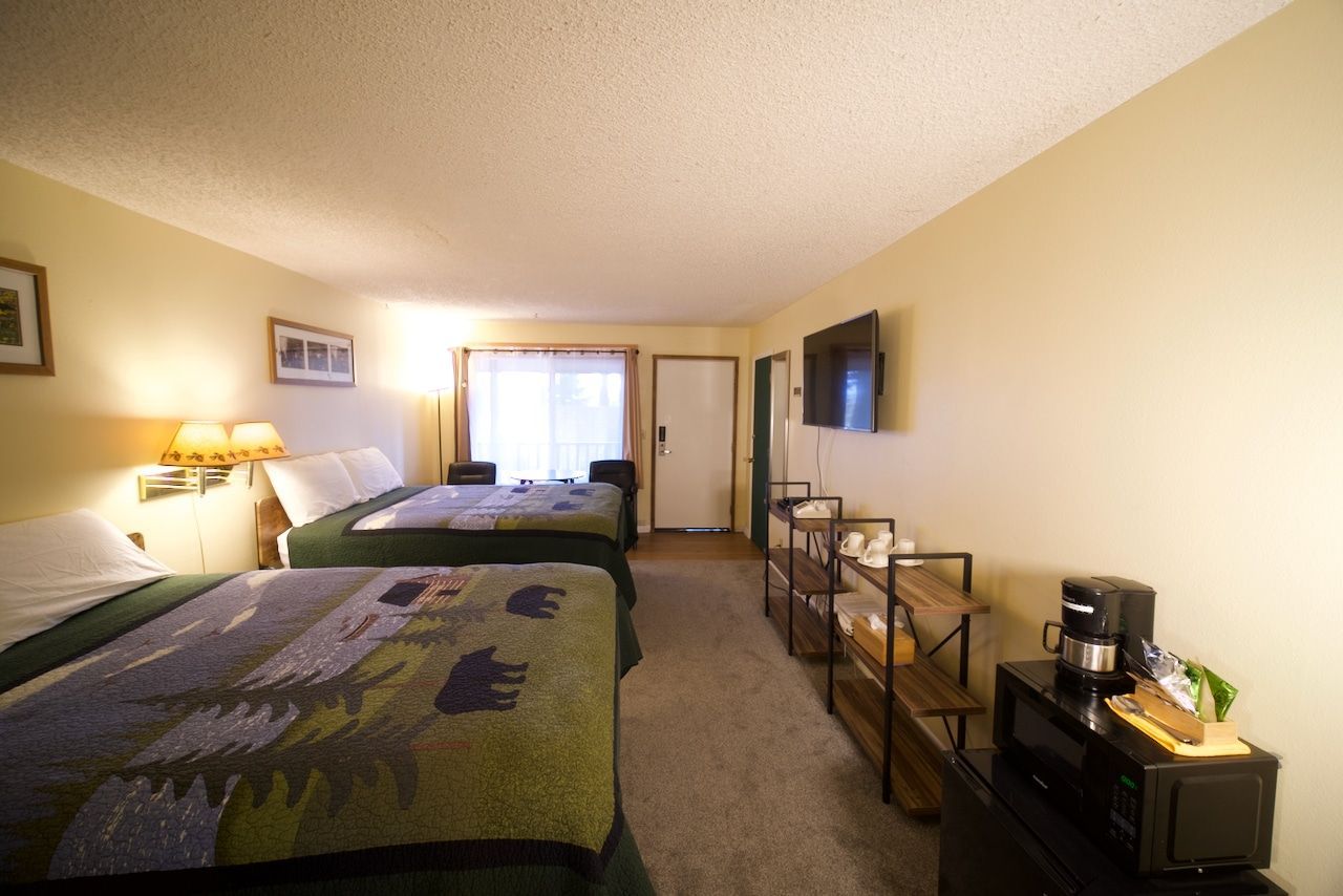 A hotel room with two beds , a microwave , and a television.