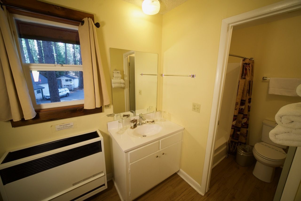 A bathroom with a sink , toilet , and window.