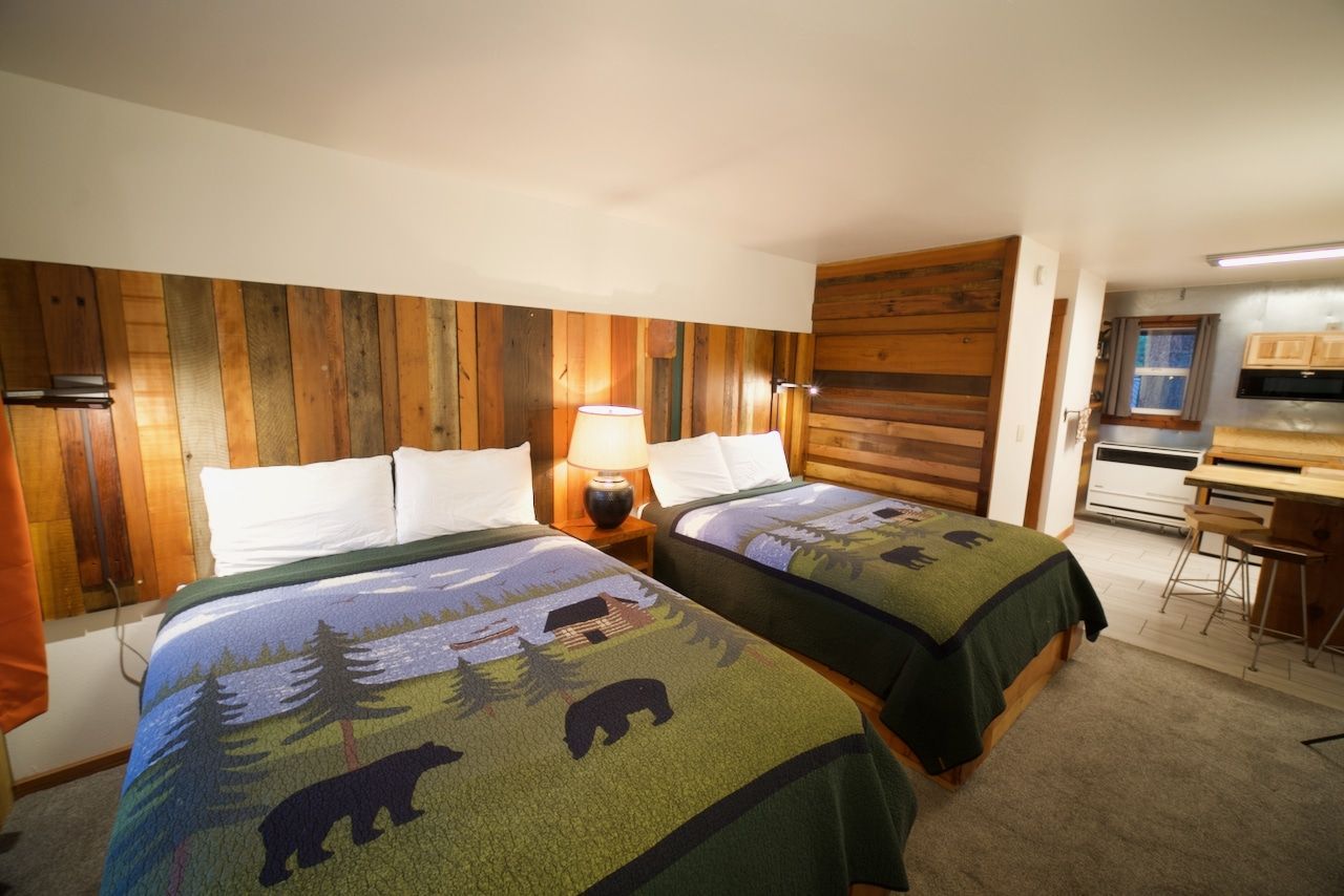 A hotel room with two beds and a wooden headboard.