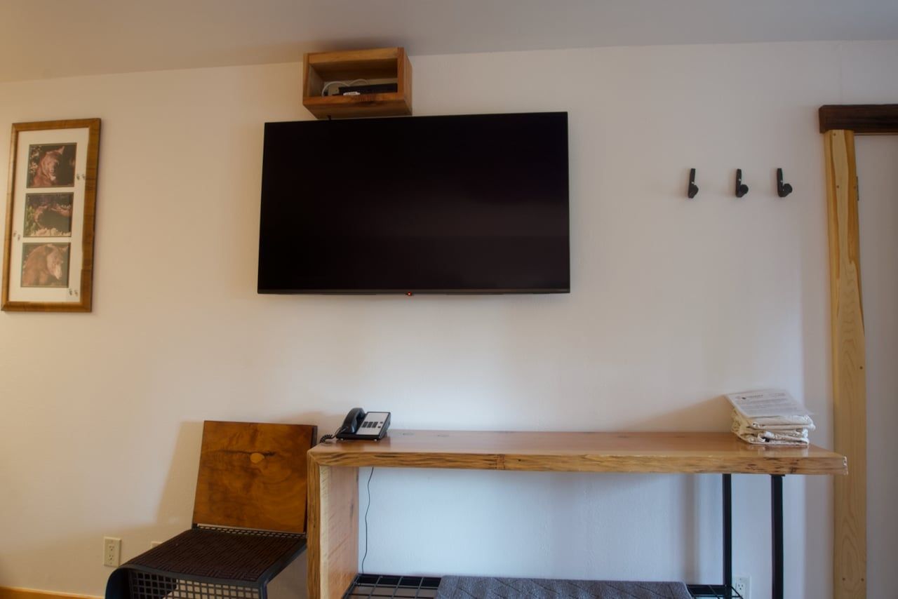 A flat screen tv is mounted on the wall above a wooden table.