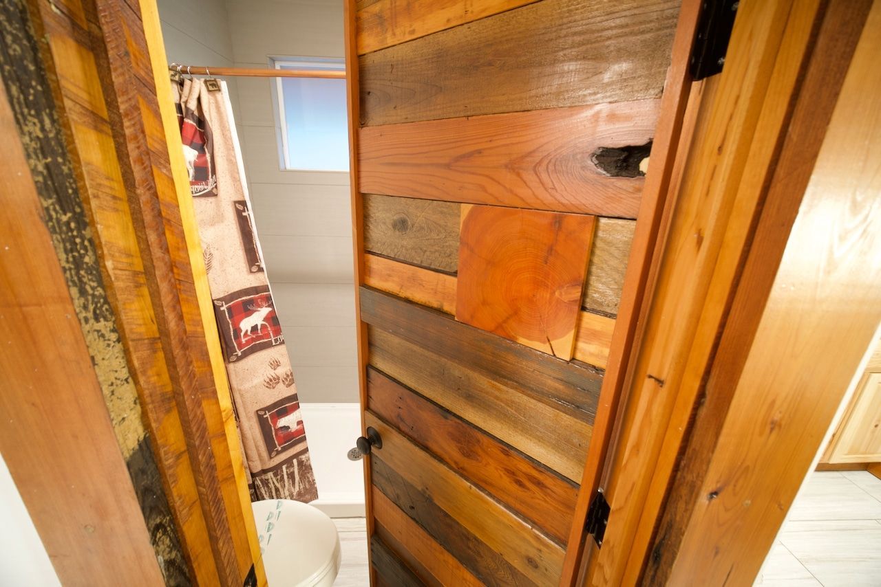 A bathroom with a wooden door and a shower curtain.