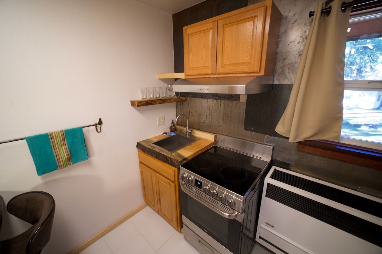 A kitchen with a stove , sink , and window