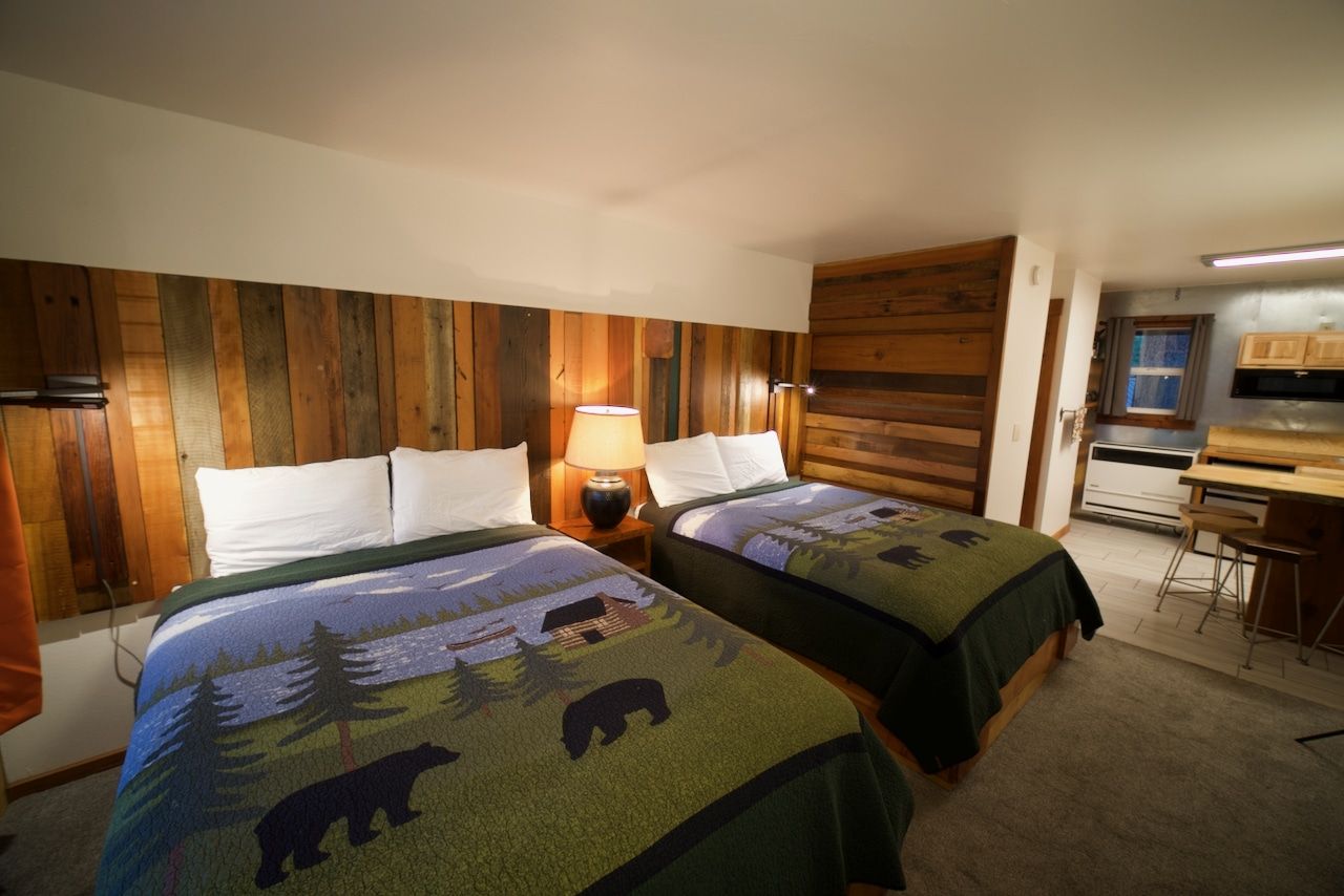 A hotel room with two beds and a wooden wall.