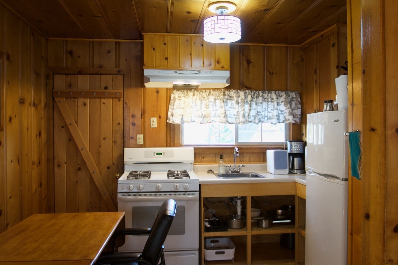 A kitchen with a stove , refrigerator , sink and table.