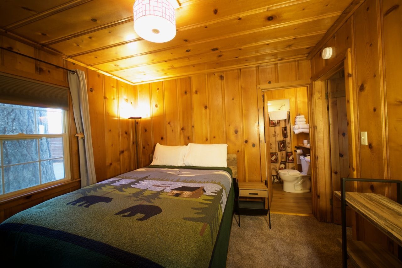 A bedroom in a cabin with a bed and a toilet.