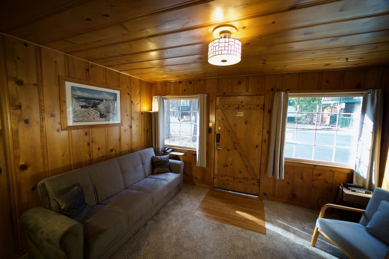 A living room with a couch , chair , table and window.