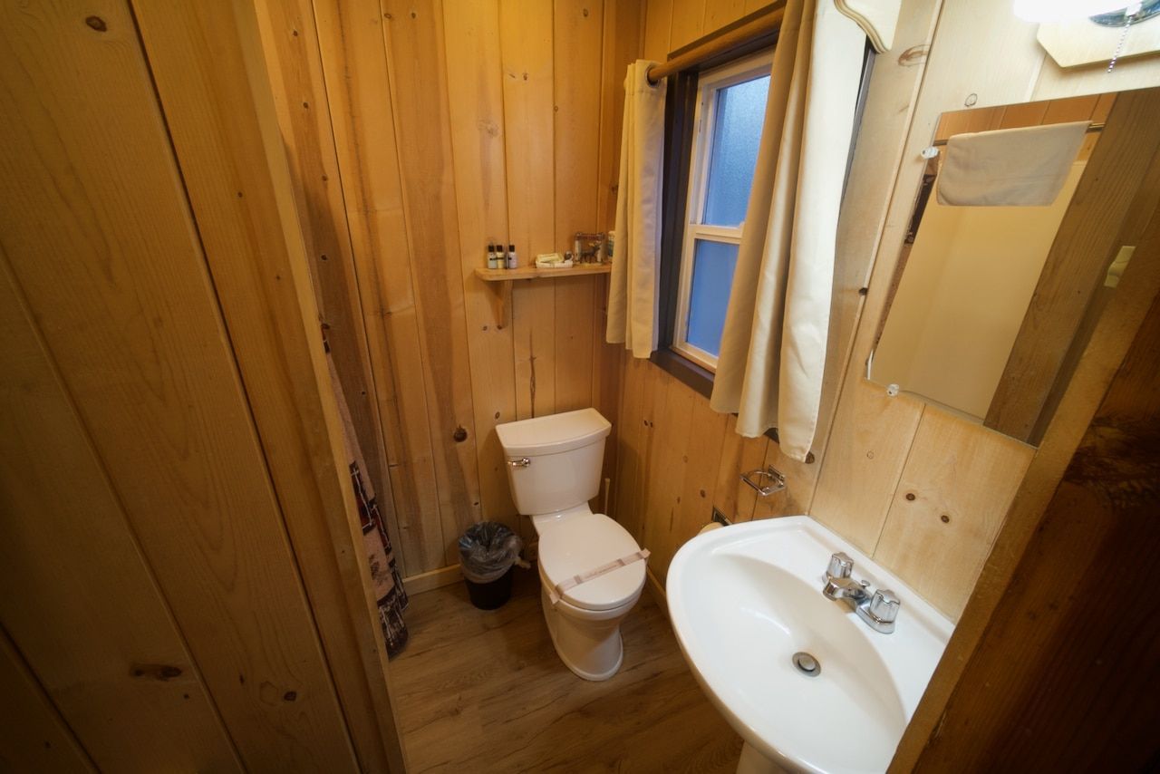 A bathroom with a toilet , sink and mirror.