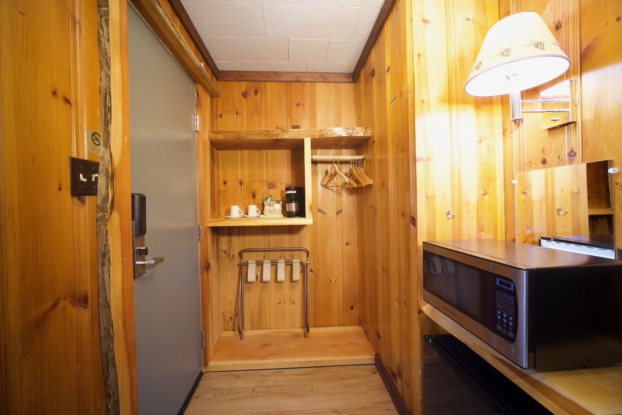 A hotel room with wood paneling and a microwave.