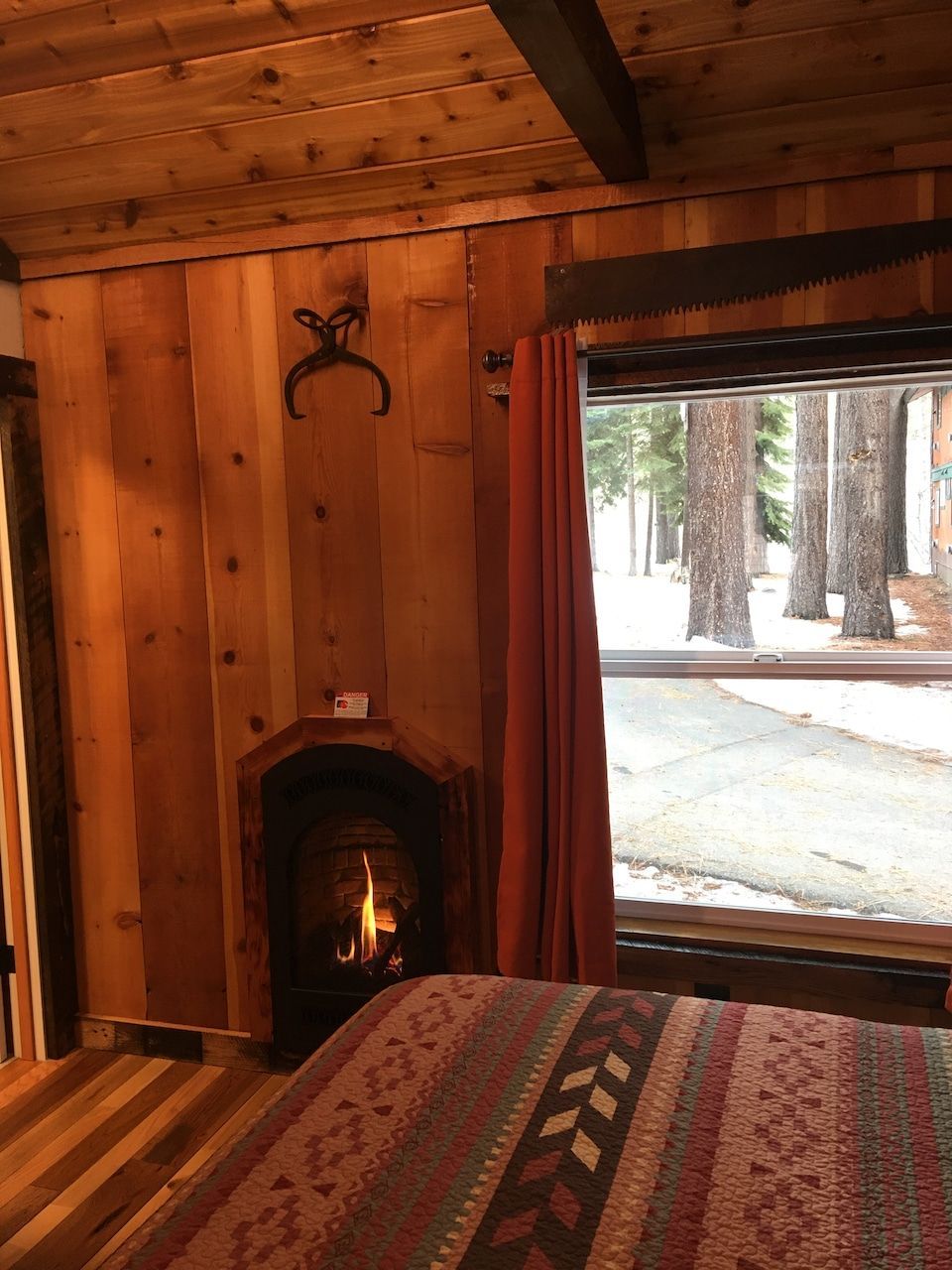 A bedroom with a fireplace and a large window.