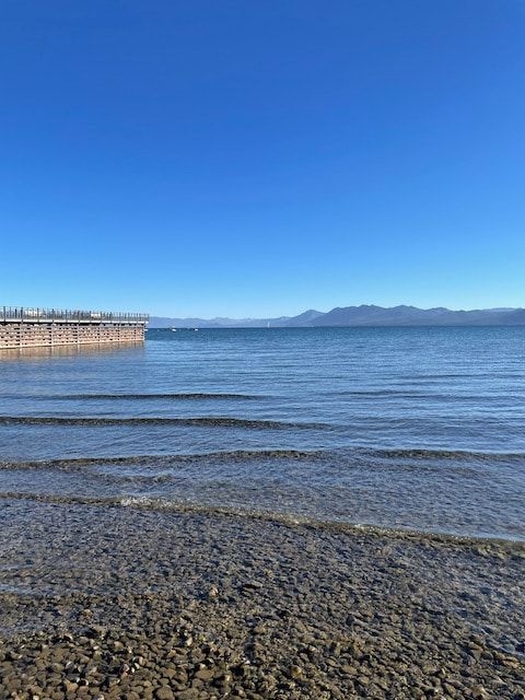 A large body of water with mountains in the background on a sunny day.