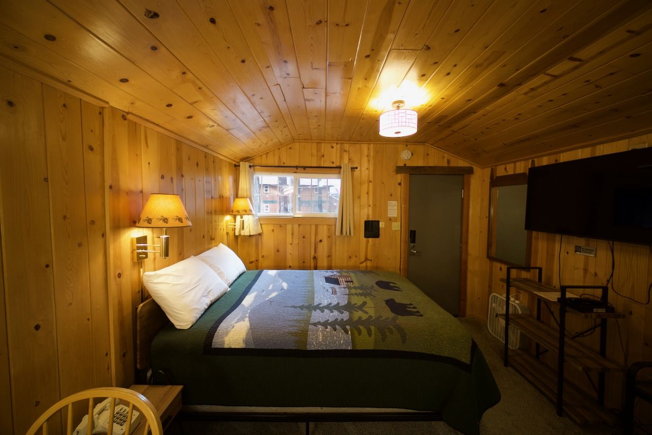 A bedroom in a cabin with a bed and a television.