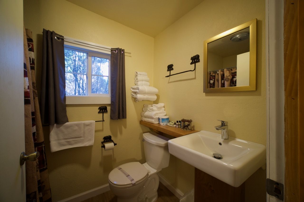 A bathroom with a toilet , sink and mirror.