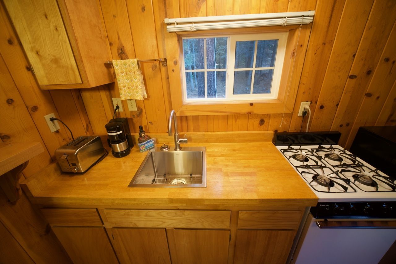 A kitchen with a sink , stove , toaster oven and window.