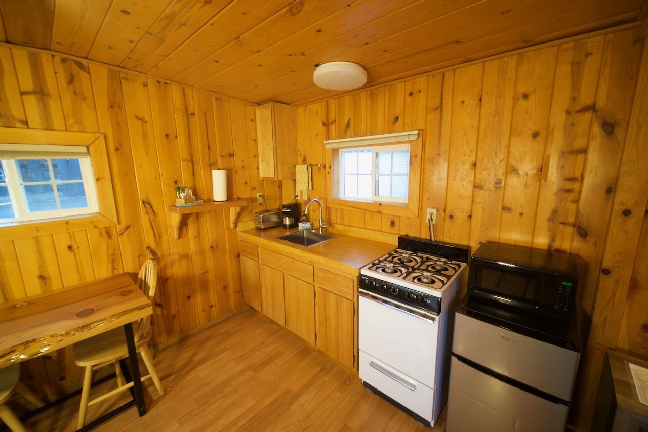 A kitchen with a stove , refrigerator , sink and window.