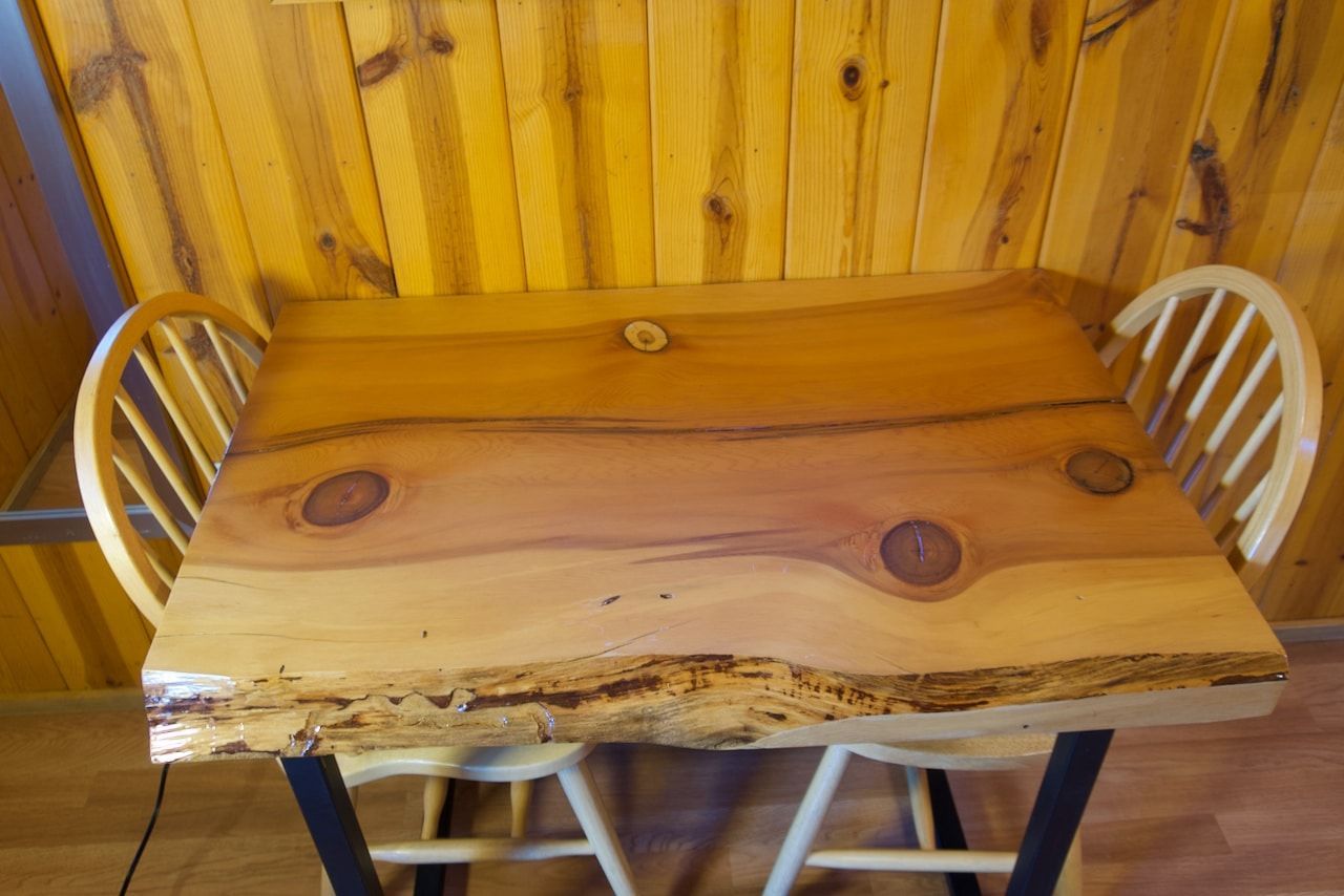 A wooden table with two chairs in front of a wooden wall.