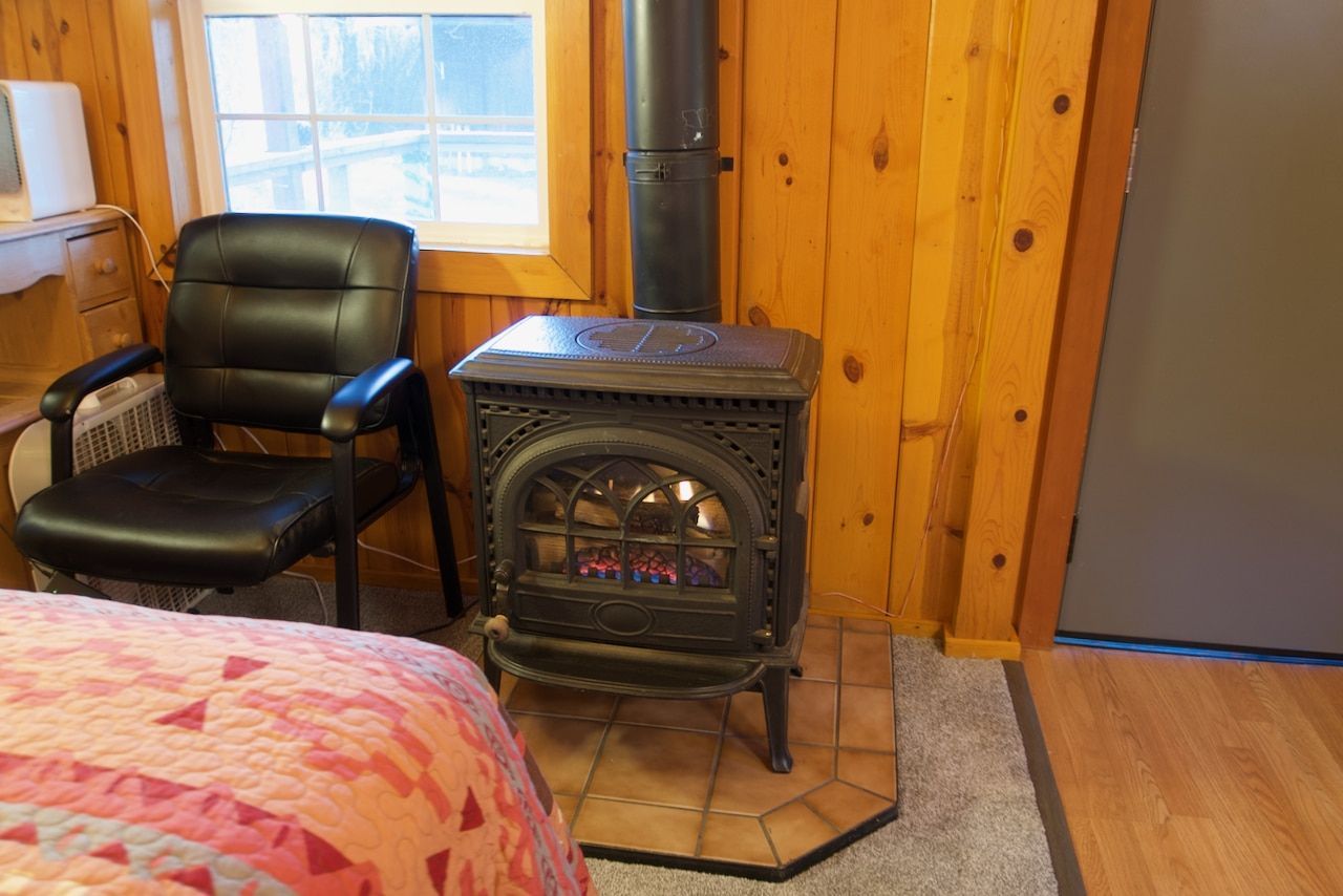 A wood stove is sitting next to a chair in a room.