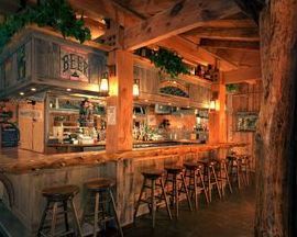 A wooden bar with stools and a sign that says beer on it.