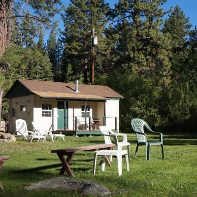 A small house with chairs and a picnic table in front of it